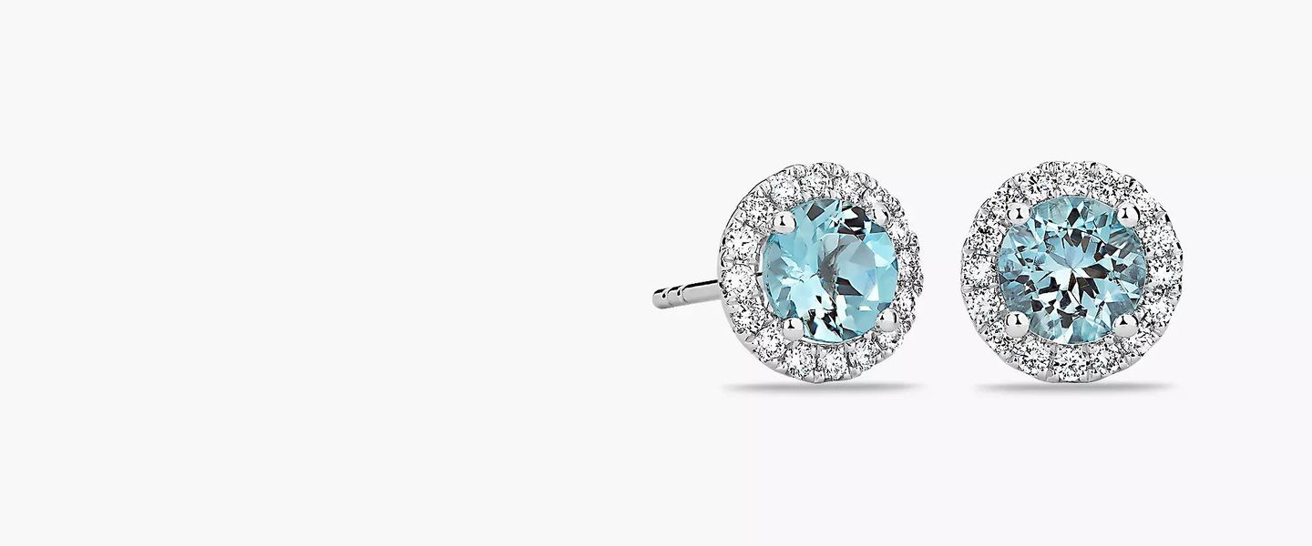 A pair of aquamarine and diamond halo birthstone stud earrings in white gold